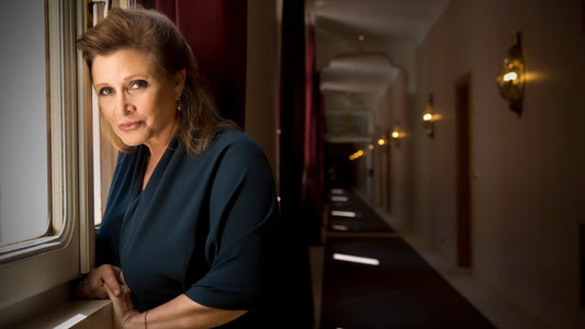 Carrie Fisher leaning against a window in a hotel hallway in 2013